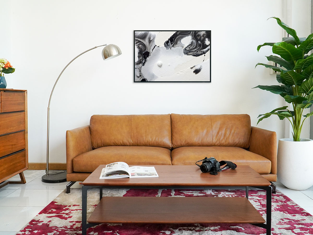 Không gian phòng khách với sofa da màu nâu, bàn gỗ và cây xanh đặt hai bên.