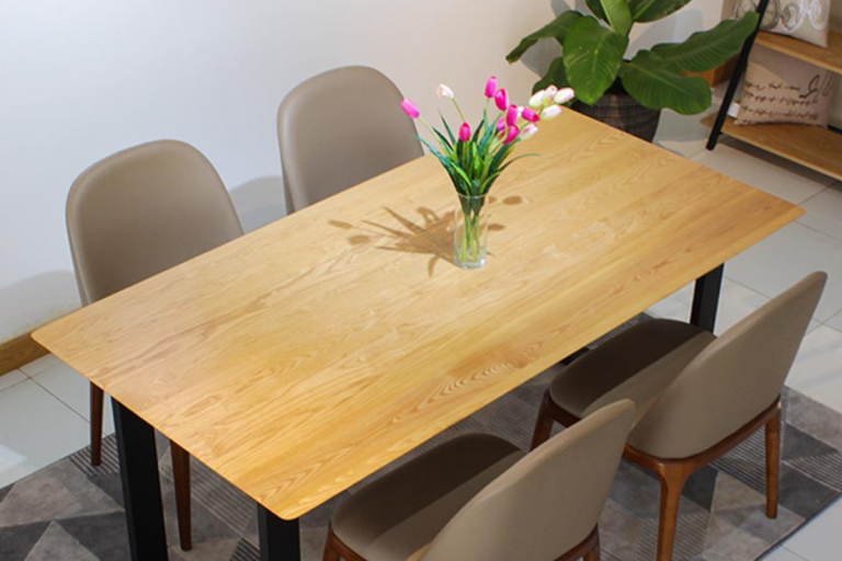 Bộ bàn ăn gỗ sáng màu với lọ hoa đặt ở giữa và bốn ghế xung quanh