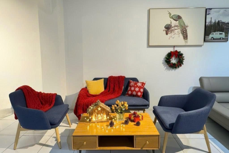 Phòng khách hiện đại với sofa xanh, bàn trà gỗ và không gian ấm cúng dưới ánh đèn vàng, kết hợp trang trí Giáng Sinh tinh tế