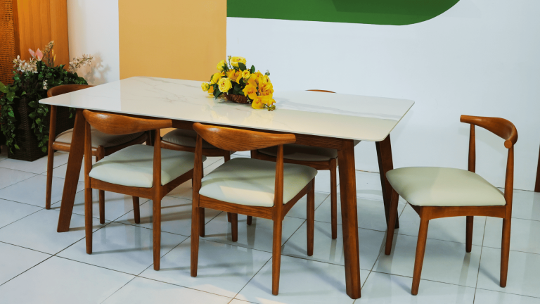 Bàn ăn mặt đá Hilton màu trắng vân đá tự nhiên, chân gỗ chắc chắn, kết hợp ghế ăn gỗ bo cong bọc nệm sáng màu, phù hợp không gian phòng ăn hiện đại và ấm cúng.